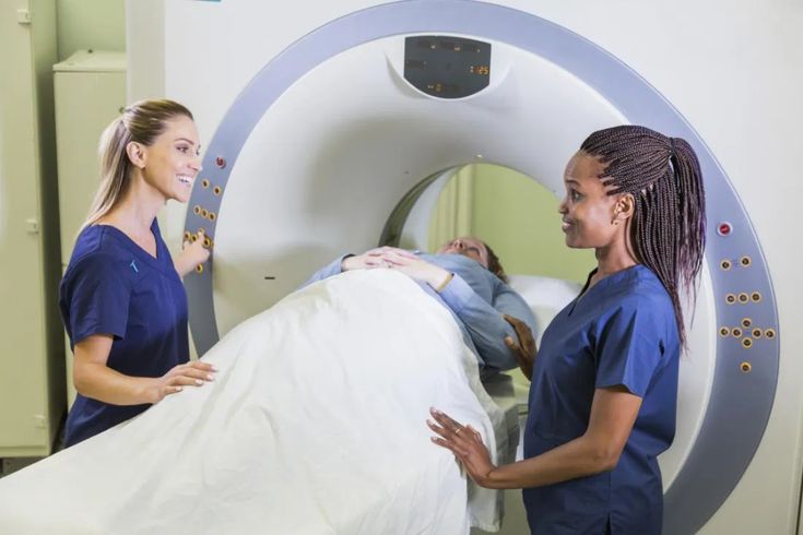 Patient being positioned for a chest CT scan by two healthcare staff